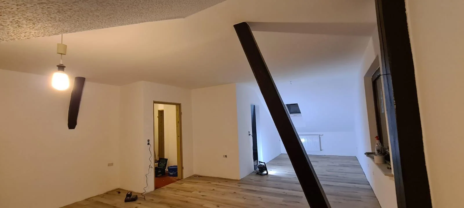 Dachgeschoss mit hellen Wand- und Deckenflächen sowie Boden in Holzoptik