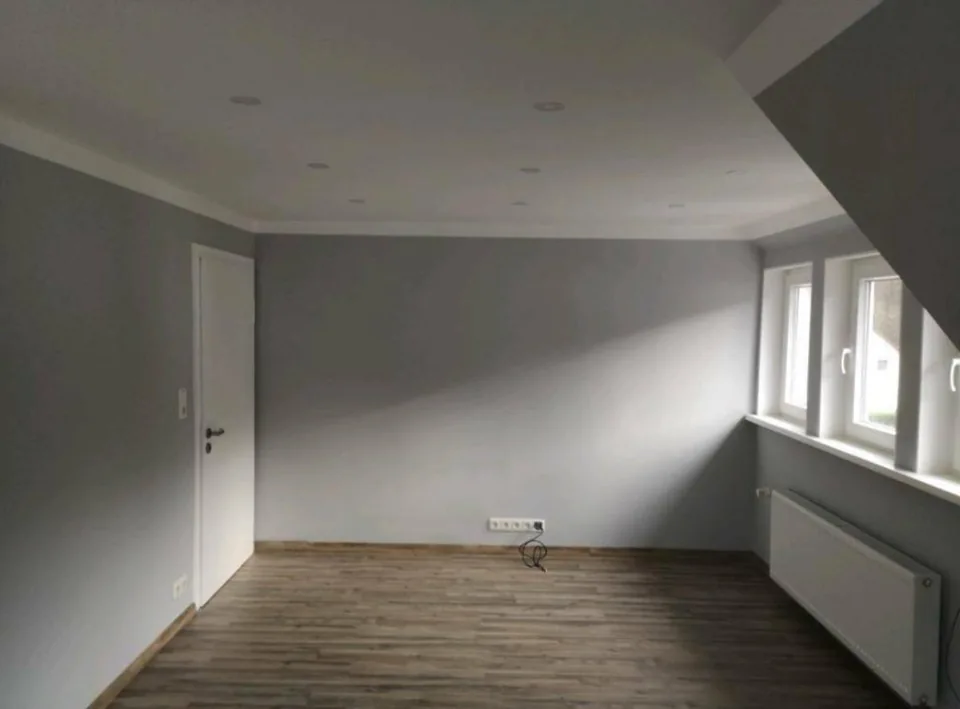 Grauer Wohnraum mit weißer Decke und Boden in Holzoptik